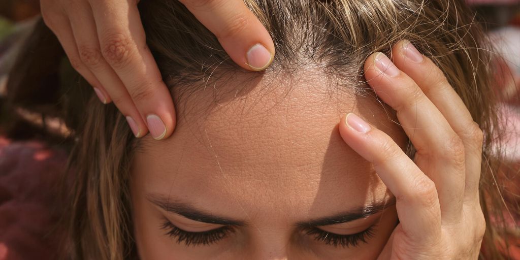 Woman gently touching her hair, looking concerned.