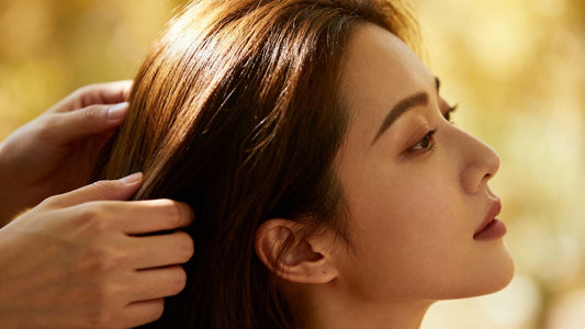 Woman's hair and scalp with gentle hands nearby.