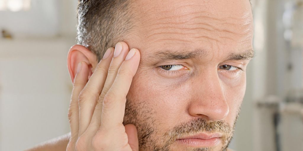 Man looking concerned, holding hair