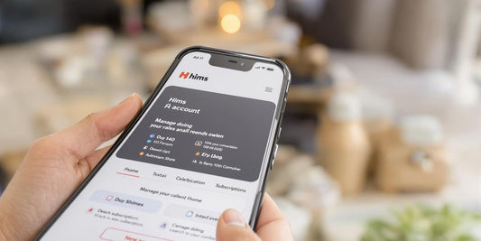 Hand holding phone showing Hims account page.